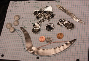 Metal Activities. From Bottom clockwise: A penny squished through a stretching machine, tin and bismuth alloy buttons, tin splotches and shreaking tin, pennies turned to "silver" and "gold."