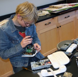 Demolishing used electronics, including old VCRs, DVD players, phones, remote controls, and calculators.